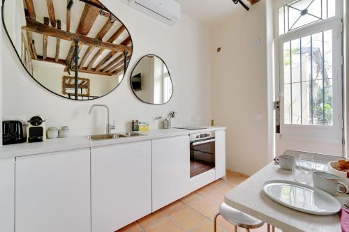 - une cuisine avec des placards blancs et un miroir rond dans l'établissement Maison à Saint-Germain-des-Prés, à Paris