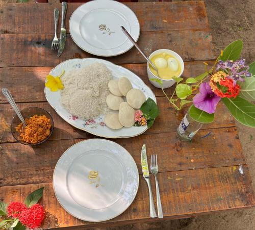 a wooden table with plates of food and flowers on it at STARFISH beach bungalow in Arugam Bay