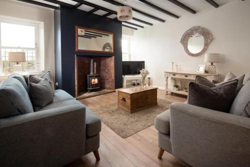 a living room with two couches and a fireplace at Hexham Cottage by Coast & Country Stays in Seahouses
