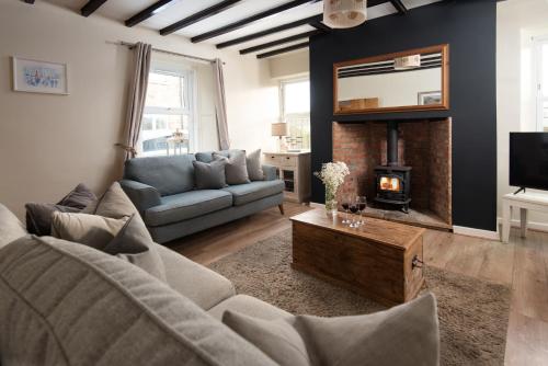 een woonkamer met een bank en een open haard bij Hexham Cottage by Coast & Country Stays in Seahouses