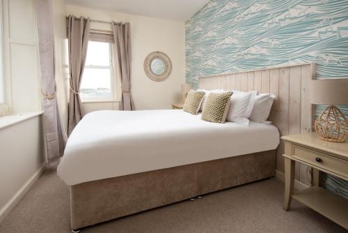 een slaapkamer met een groot wit bed en een raam bij Hexham Cottage by Coast & Country Stays in Seahouses