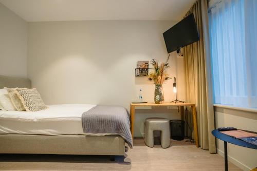a bedroom with a bed and a table and a television at Hotel du Bassin in Ostend