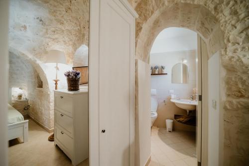 a bathroom with a stone wall and a sink and a toilet at Antica Tenuta dei Trulli in Alberobello