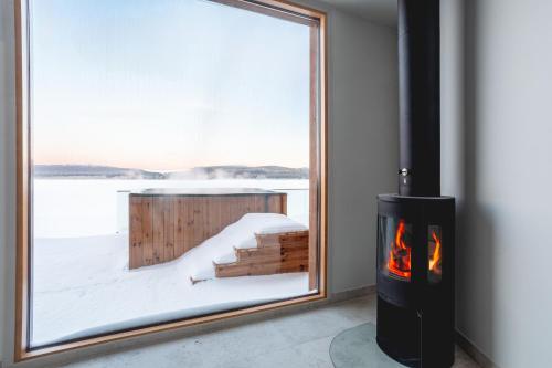 a fireplace in a room with a view of the snow at Stay North - Joiku - Kaltio in Äkäslompolo