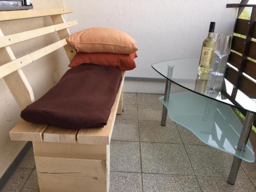 a bench with a glass table and a bottle of wine at Apartment Panoramablick in Bad Mergentheim