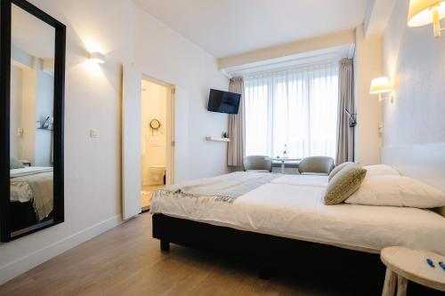 a bedroom with a large bed and a mirror at Hotel du Bassin in Ostend