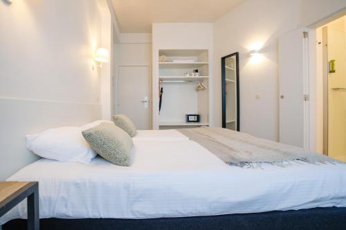 a bedroom with a large white bed with pillows at Hotel du Bassin in Ostend