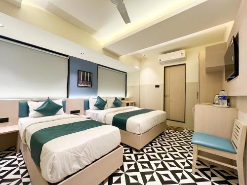 a hotel room with two beds and a chair at Bandra Stays in Mumbai
