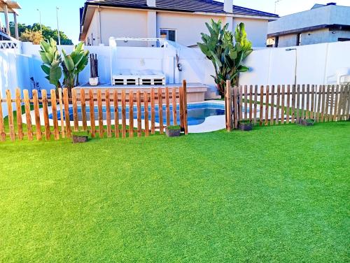 een houten hek in een tuin met een zwembad bij Chalets en Punta Umbría in Punta Umbría