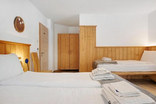 a bedroom with two beds and wooden cabinets at Agritur Maso Flonkeri in Bosentino