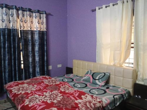a bedroom with a bed with purple walls and curtains at Kingsman in Katra