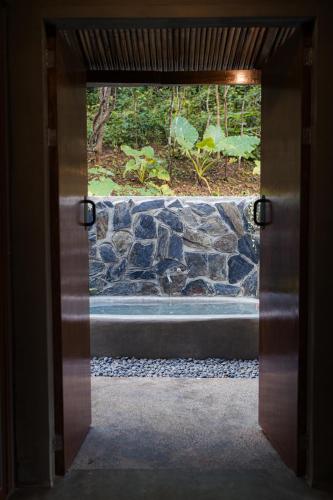 an open door with a view of a stone wall at Inigtan Lio Villas in El Nido