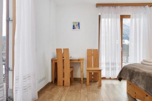 a bedroom with a bed and a desk and a window at Agritur Maso Flonkeri in Bosentino