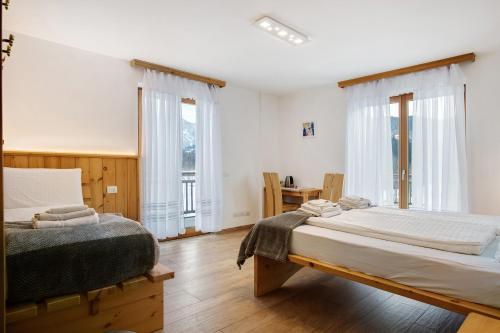 two beds in a room with two windows at Agritur Maso Flonkeri in Bosentino