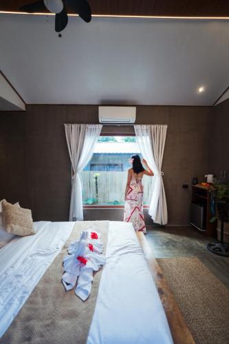 a woman standing in a bedroom looking out the window at Inigtan Lio Villas in El Nido