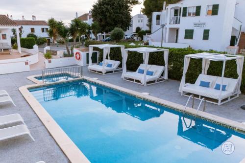 a swimming pool with two chairs and a gazebo at Apartamentos Annabel's II in Cala Galdana
