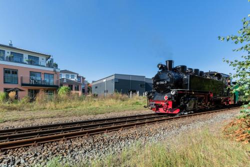 a train traveling down the tracks near a building at Alte Fischfabrik in Putbus