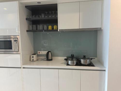 a kitchen with white cabinets and pots on a stove at KLCC Sky Villa Suites Platinum in Kuala Lumpur