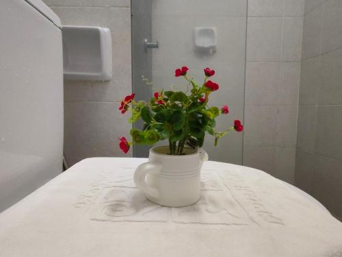 a vase with red flowers on a table in a bathroom at YNWA Shankly Stay, Near KLIA in Sepang
