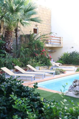 a swimming pool with lounge chairs next to a building at Charming Xagħra Farmhouse with Pool, Garden & Spacious, Gozo by 360 Estates in Xagħra