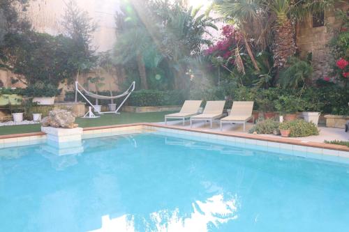 a swimming pool with two lounge chairs and a hammock at Charming Xagħra Farmhouse with Pool, Garden & Spacious, Gozo by 360 Estates in Xagħra