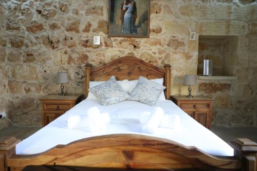 a bedroom with a large wooden bed with two night stands at Charming Xagħra Farmhouse with Pool, Garden & Spacious, Gozo by 360 Estates in Xagħra