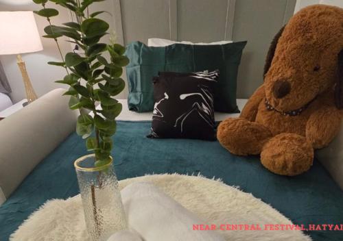 a teddy bear and a vase with a plant on a couch at SridaHouse#Near Central Festival Hat Yai in Sathani Khlong Rian