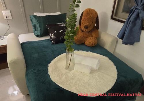 a teddy bear sitting on a bed with a vase at SridaHouse#Near Central Festival Hat Yai in Sathani Khlong Rian