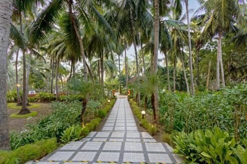 a walkway lined with palm trees in a park at Sterling Palavelli Godavari in Rāzole