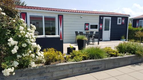 a house with a deck with a table and chairs at Olmenduin Chalet Olm Zeeland in Serooskerke