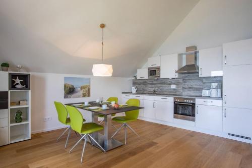 a kitchen with a table and green chairs at Fewo Reeder's Topp by Seeblick Ferien ORO, Penthouse,Panoramablick,Sauna in Olpenitz
