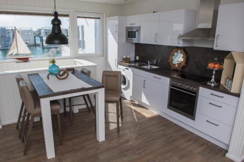 eine Küche mit weißen Schränken, einem Tisch und einem Esszimmer in der Unterkunft Schwimmendes Ferienhaus Antares One by Seeblick Ferien ORO, rundum Wasser, Sauna in Olpenitz