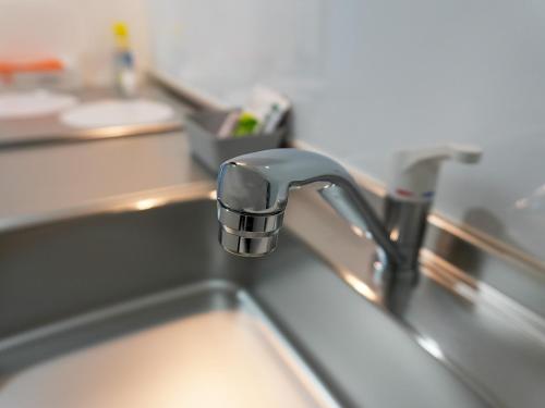 a sink with a faucet in a kitchen at OUCHI HOTEL Onaganishi in Hiroshima