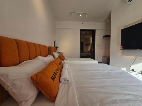 a large bed with white sheets and orange pillows at K Avenue Kota Kinabalu by Merveille - Sabah in Donggongon