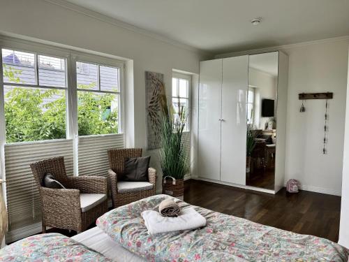 a bedroom with a bed and chairs and a mirror at Traumferienhaus Sliminde by Seeblick Ferien ORO, direkte Wasserlage E-Säule 6 Pers in Olpenitz