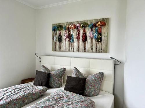 a bedroom with a bed with pillows and a painting on the wall at Traumferienhaus Sliminde by Seeblick Ferien ORO, direkte Wasserlage E-Säule 6 Pers in Olpenitz