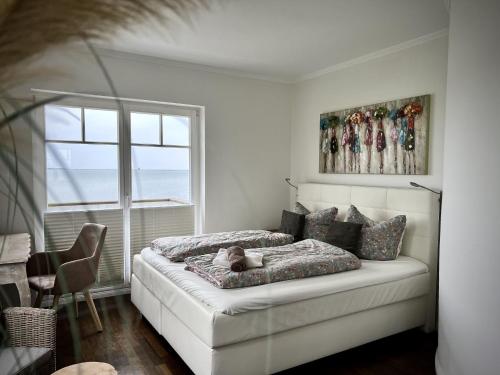a white bedroom with a bed and a window at Traumferienhaus Sliminde by Seeblick Ferien ORO, direkte Wasserlage E-Säule 6 Pers in Olpenitz
