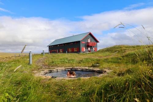 a person swimming in a pond in front of a barn at Laugarfell Accommodation & Hot Springs in Laugarfell