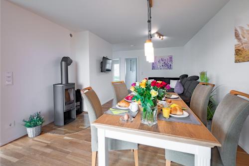 a dining room and living room with a table with flowers at Fewo MEERwert by Seeblick Ferien ORO, Familienfreundlich, Sauna, Kamin,XL Dusche in Olpenitz