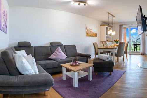 a living room with a couch and a table at Fewo MEERwert by Seeblick Ferien ORO, Familienfreundlich, Sauna, Kamin,XL Dusche in Olpenitz