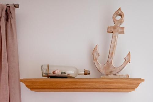 a wooden shelf with a bottle and a anchor at Fewo MEERwert by Seeblick Ferien ORO, Familienfreundlich, Sauna, Kamin,XL Dusche in Olpenitz