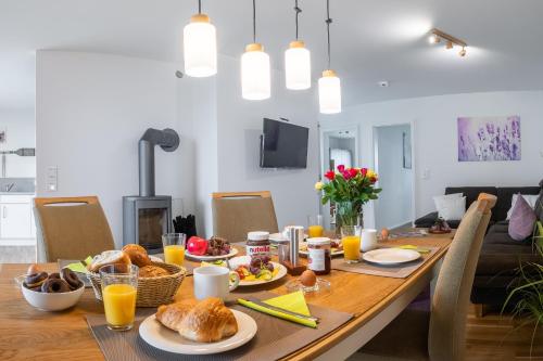 a dining room table with breakfast foods and orange juice at Fewo MEERwert by Seeblick Ferien ORO, Familienfreundlich, Sauna, Kamin,XL Dusche in Olpenitz