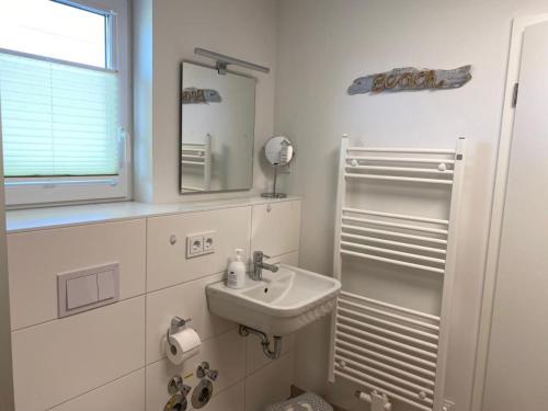 a white bathroom with a sink and a mirror at Fewo MEERwert by Seeblick Ferien ORO, Familienfreundlich, Sauna, Kamin,XL Dusche in Olpenitz