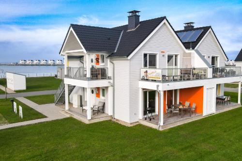 a large white house with an orange at Fewo MEERwert by Seeblick Ferien ORO, Familienfreundlich, Sauna, Kamin,XL Dusche in Olpenitz