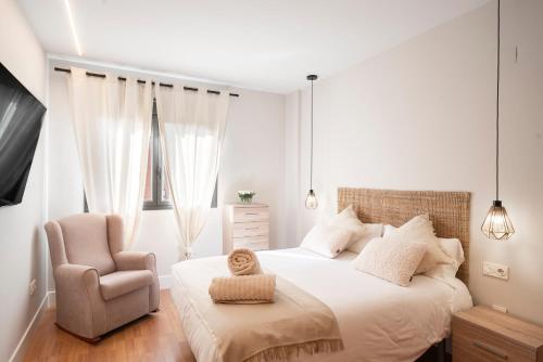 a white bedroom with a bed and a chair at EnjoyGranada New Suite EMIR in Granada