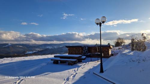 a log cabin in the snow with a light at Domki 4 pory roku in Koniaków