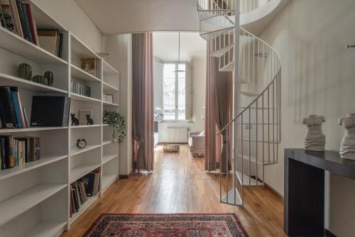 a spiral staircase in a living room with bookshelves at Single House in Pisa