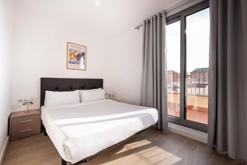 ein Schlafzimmer mit einem weißen Bett und einem großen Fenster in der Unterkunft Sweett - Harmony Central in Barcelona