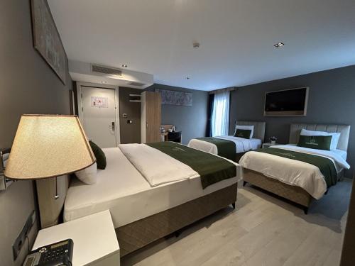 a hotel room with two beds and a television at Gardenmode Airport Hotel in Taşoluk