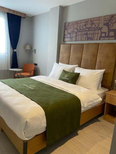 a bedroom with a large bed with a headboard at Gardenmode Airport Hotel in Taşoluk